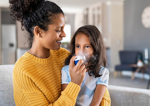 mother helping sick daughter use a nebulizer