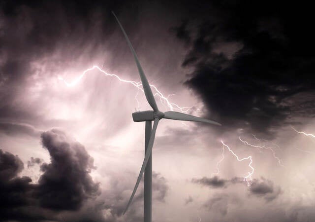 shot of a single windmill against a backdrop of storm clouds and lightning